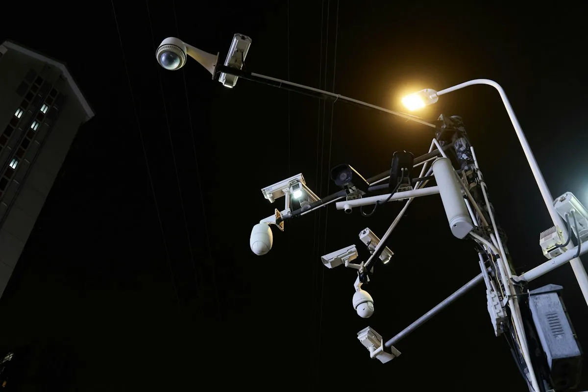 A street-light pole at night bristling with CCTV cameras